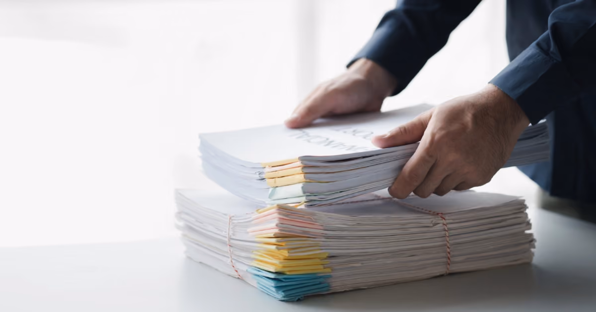 A person placing a big stack of documents on a table