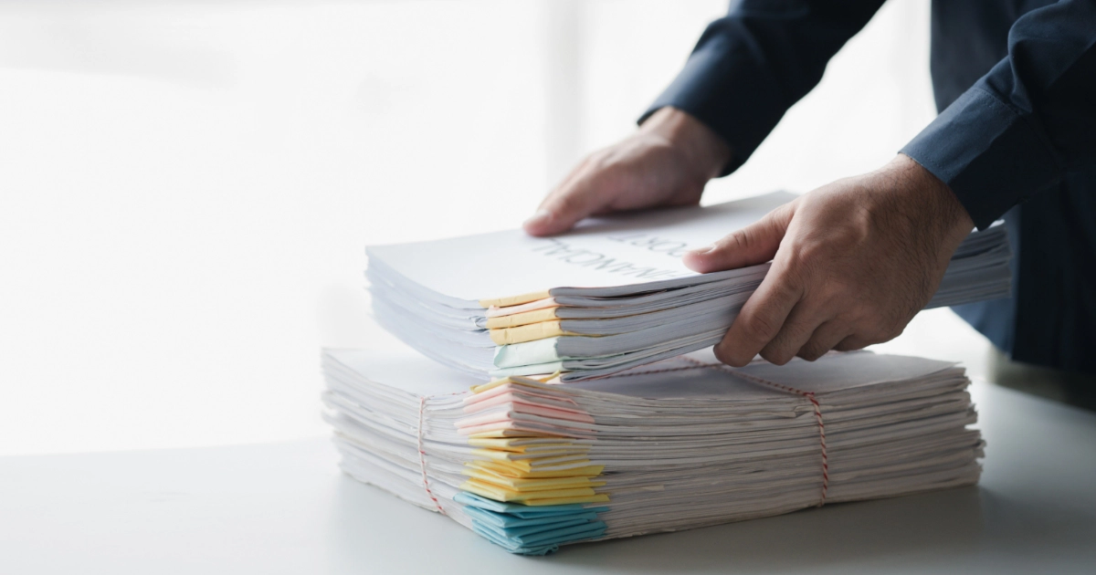 A person placing a big stack of documents on a table