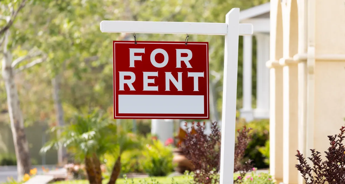 A red "For Rent" sign outside a home