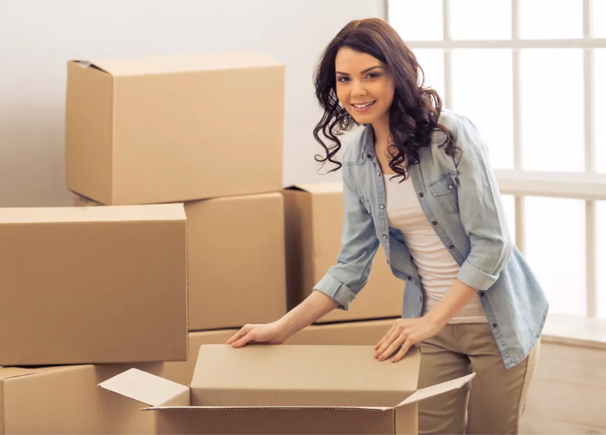 Smiling young woman surrounded by moving boxes.