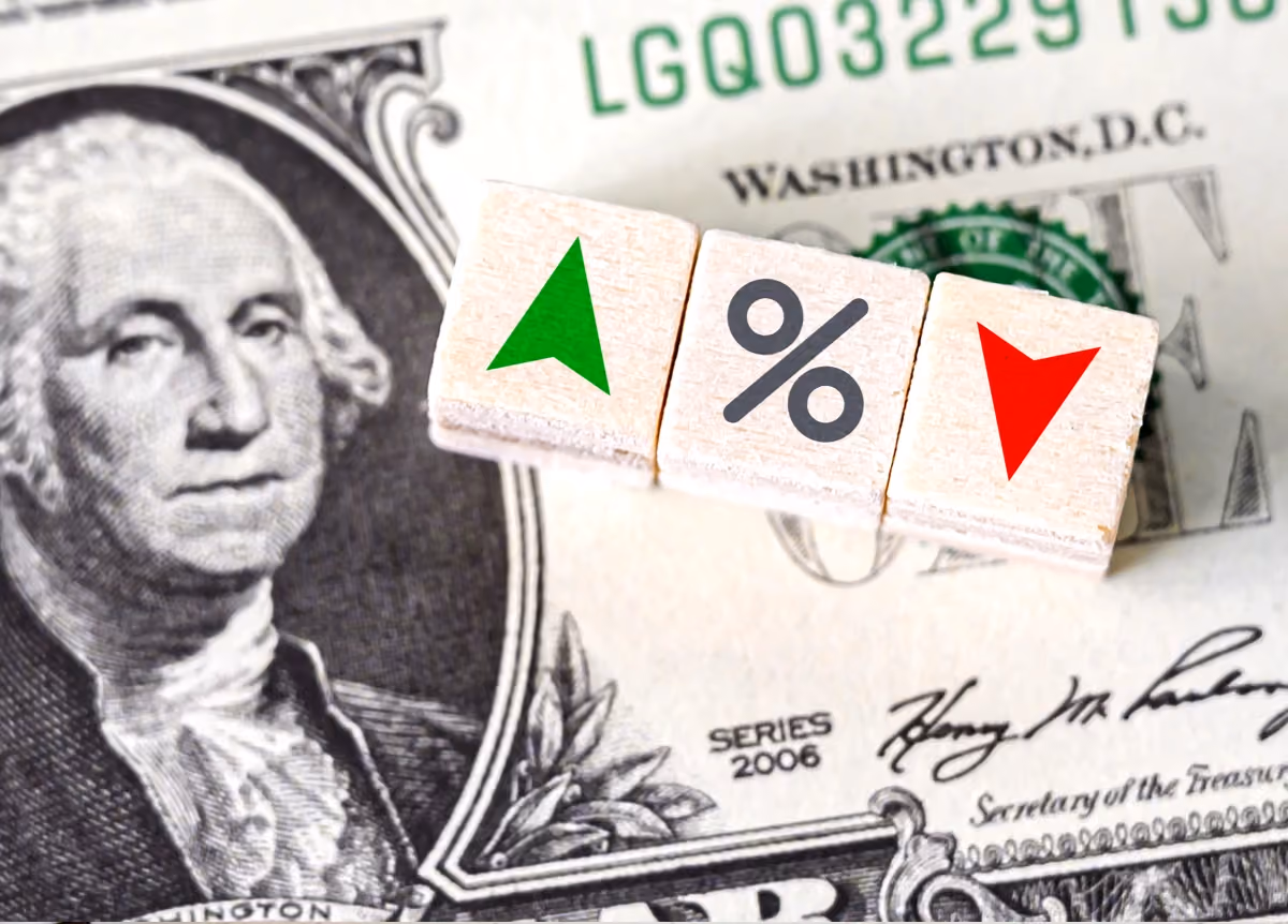 Percentage icon and up and down arrows on wooden cubes on top of US one-dollar bill