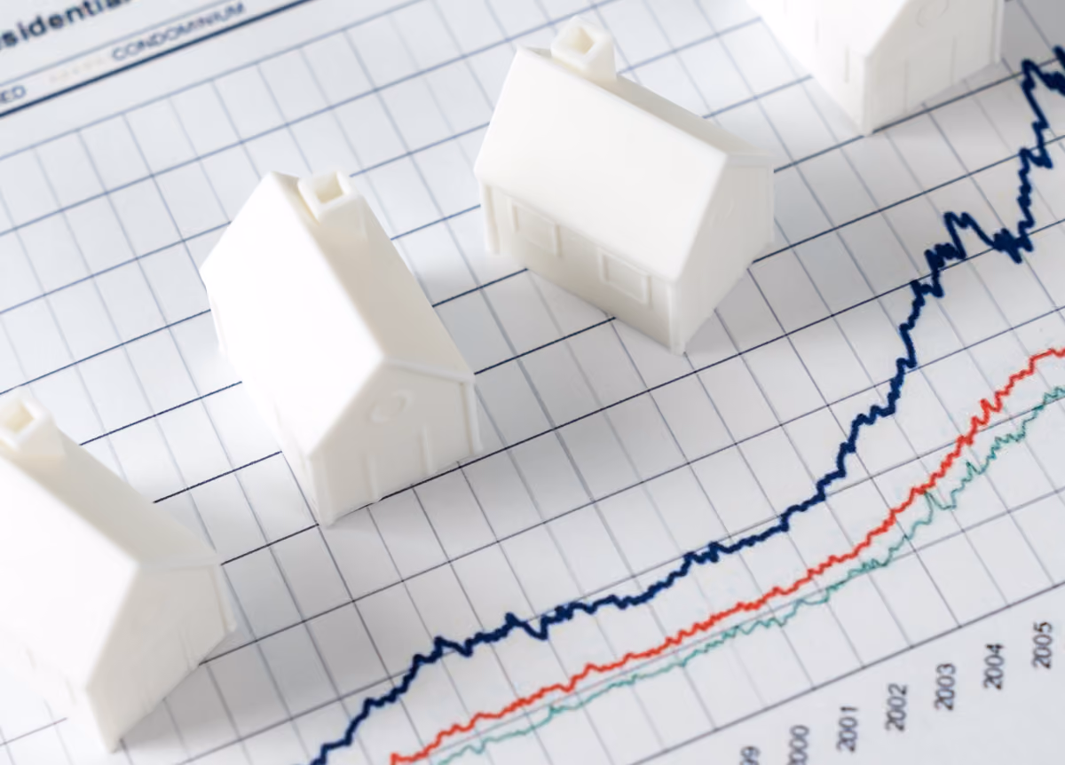 White miniature house models on graph indicating growth in real estate prices market