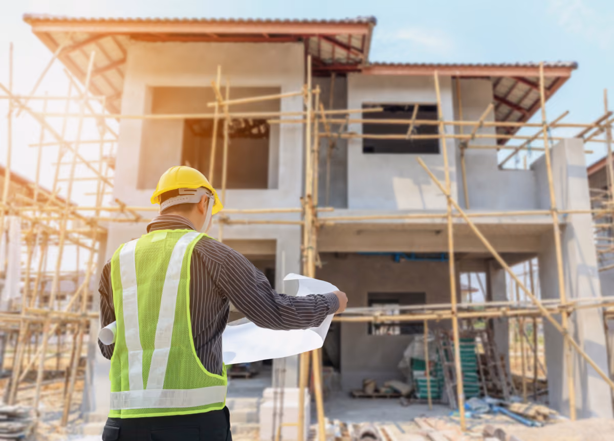 Construction worker looks at blueprints for construction site in front of him