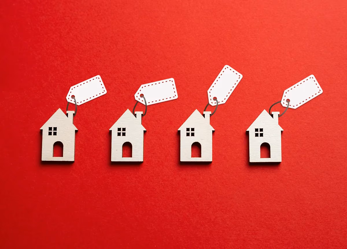Mini wooden houses with price tags on red background
