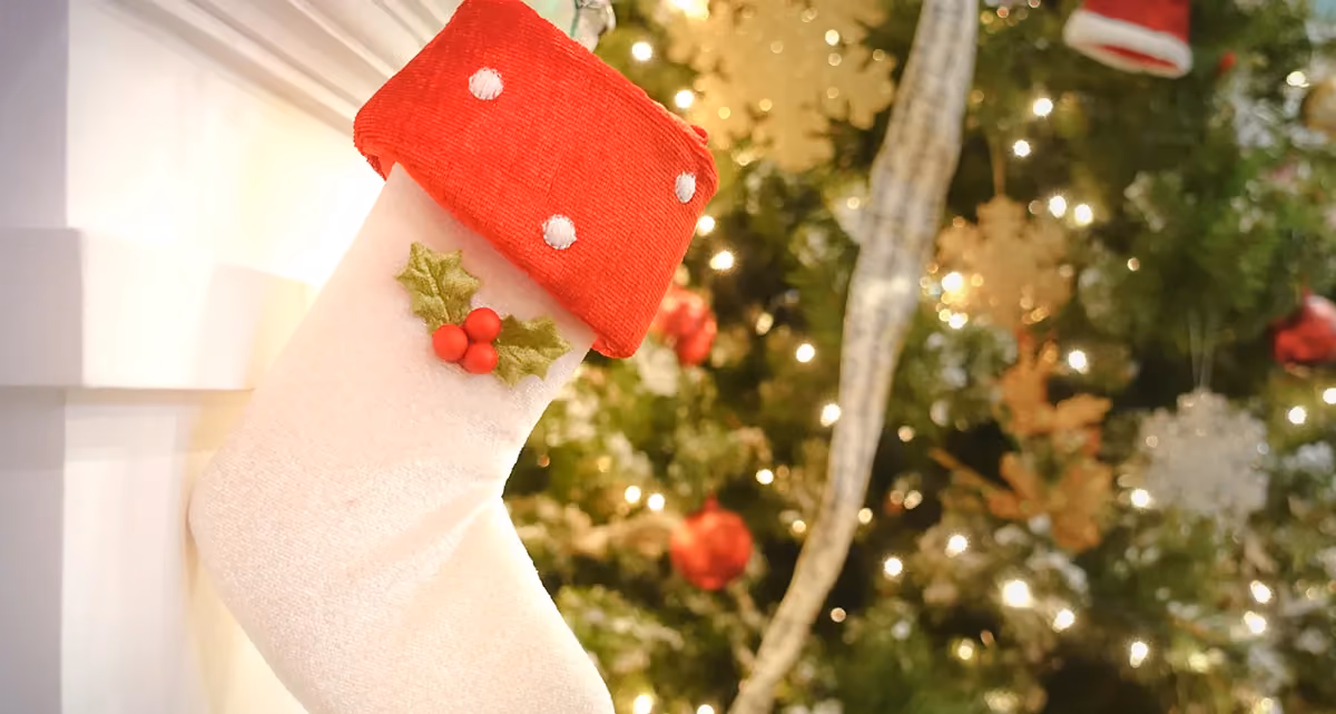 A Christmas stocking with a decorated Christmas tree in the background