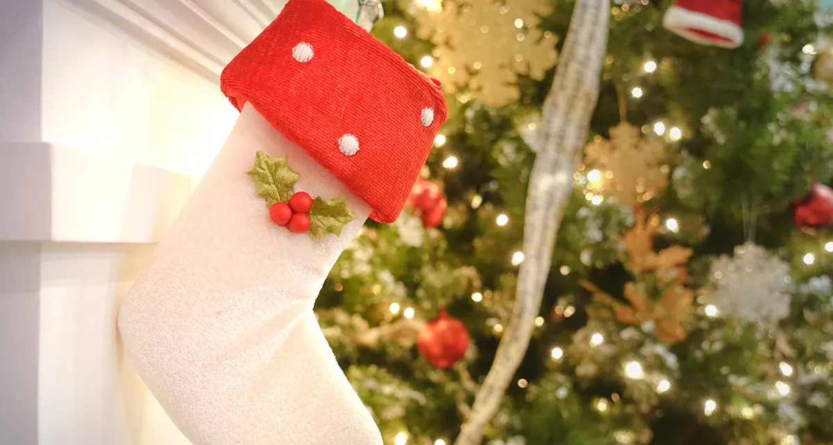 A Christmas stocking with a decorated Christmas tree in the background