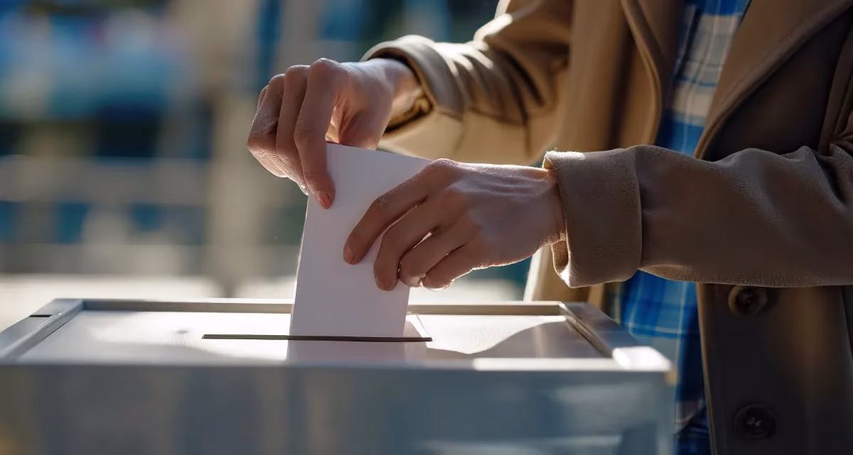 A person putting a piece of paper into a ballot box