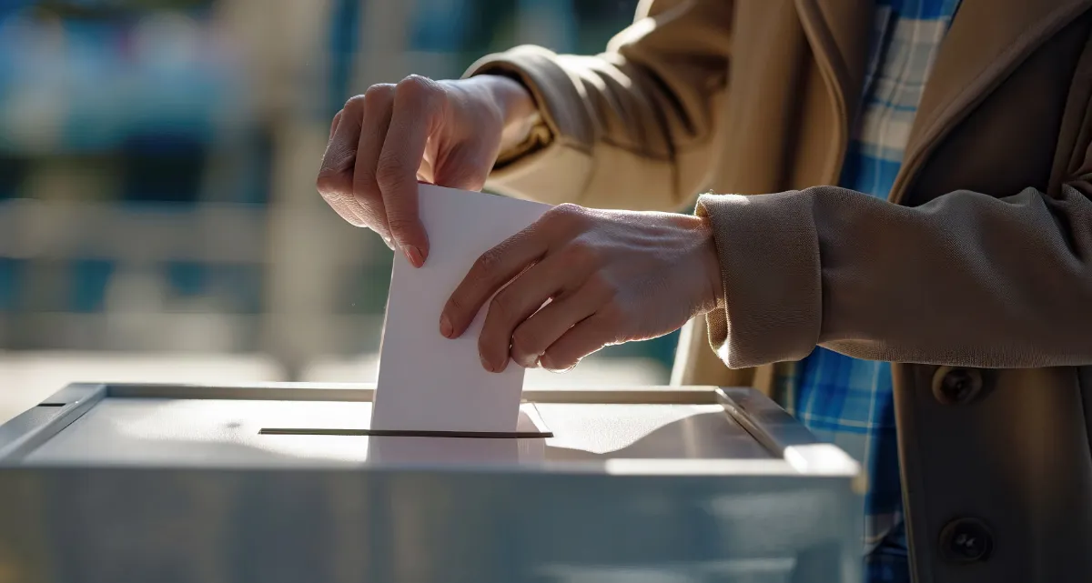 A person putting a piece of paper into a ballot box