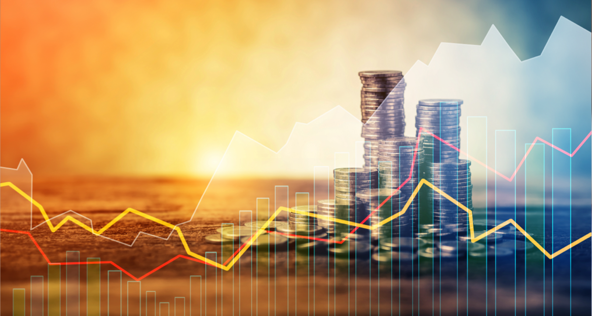 Graph trend lines in front of a stack of coins and a sunset