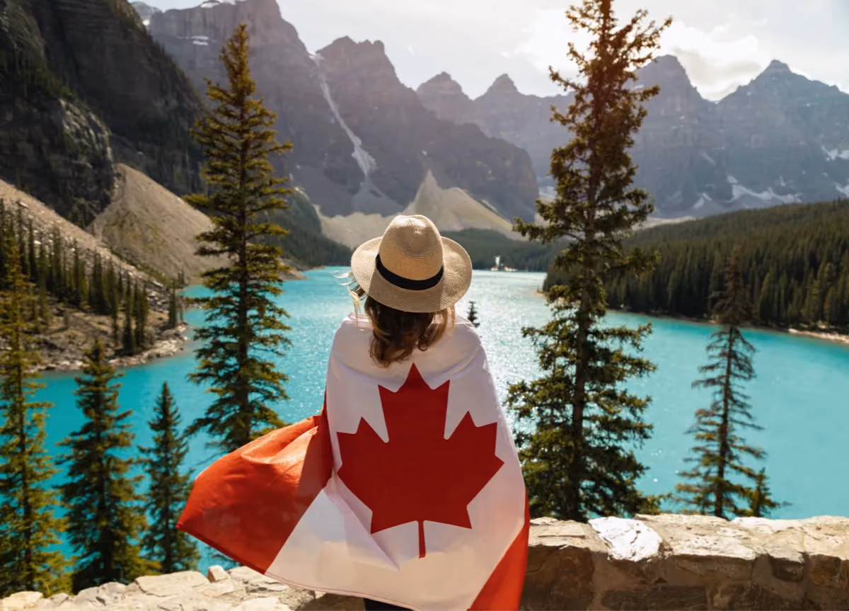 Woman draped in Canadian flag standing in front of Moraine Lake in Alberta