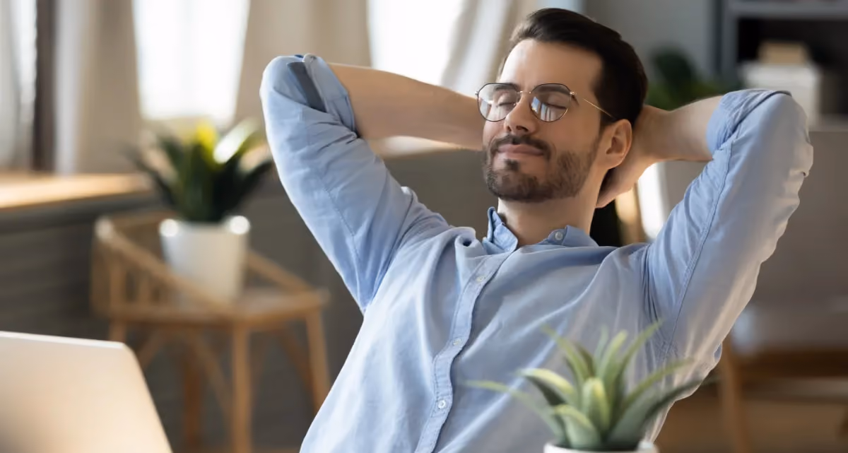 A relaxed looking man leaning back in a chair with his hands behind his head