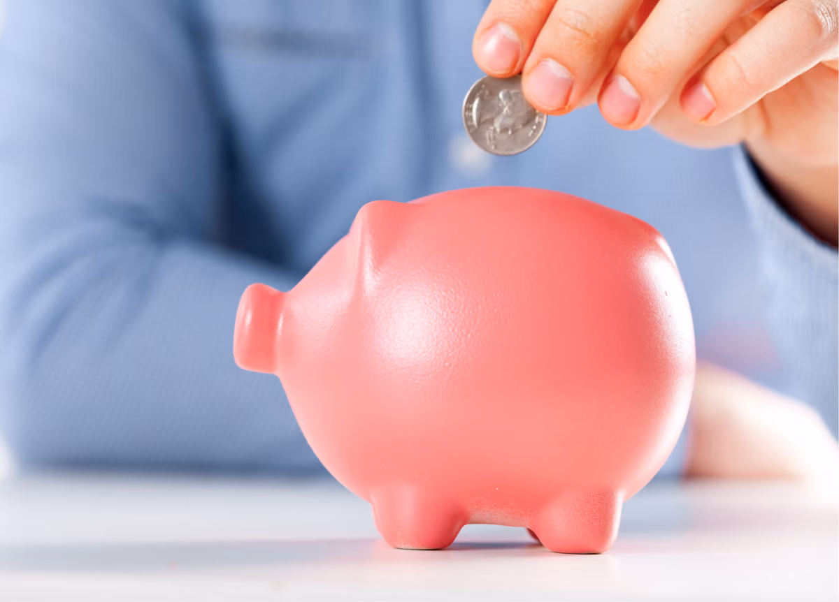 Man putting a quarter in a bright pink piggy bank