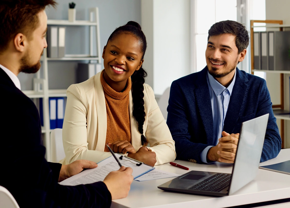 Smiling young couple speaking with broker in office setting