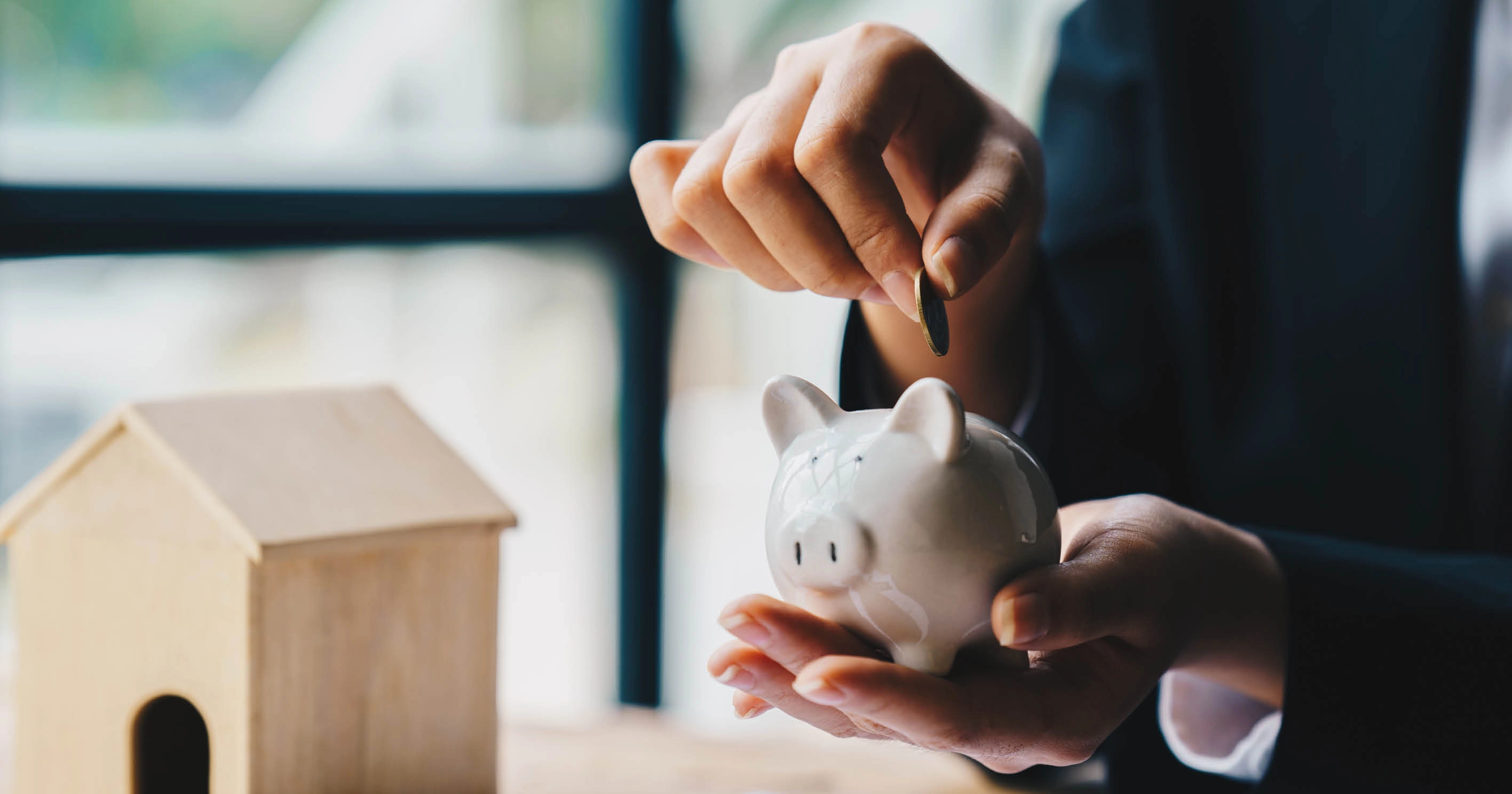 A person putting a coin into a piggy bank
