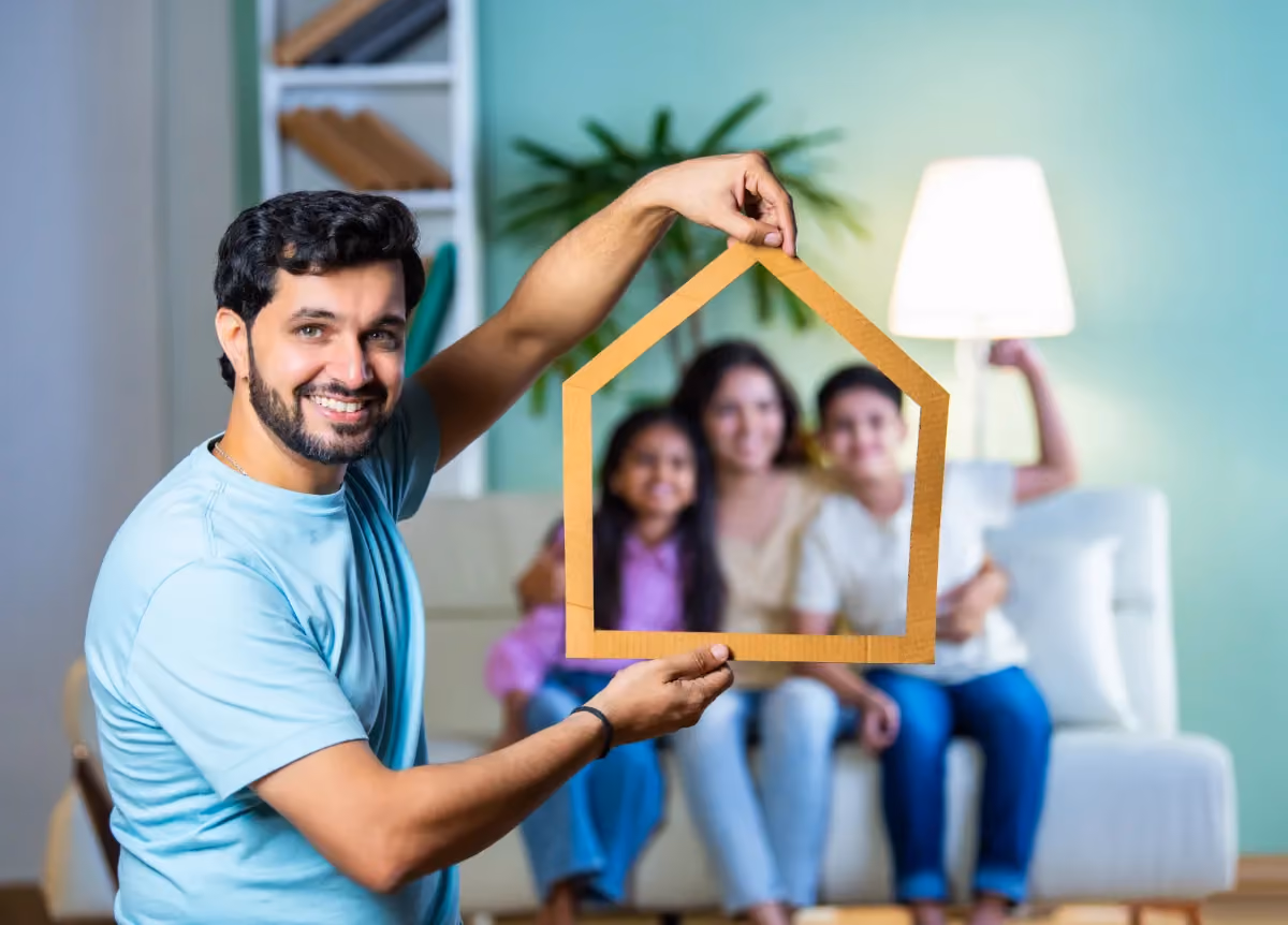 Man holds frame of a house around his family