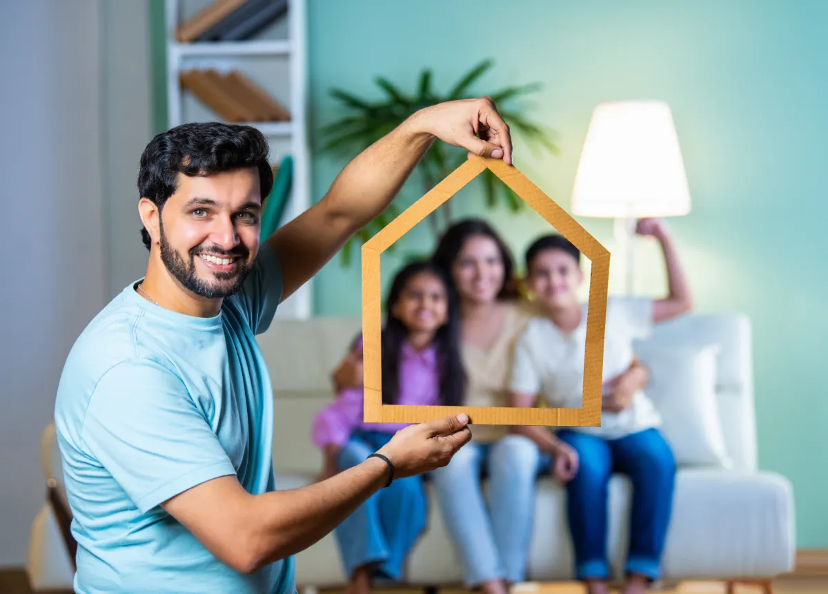 Man holds frame of a house around his family