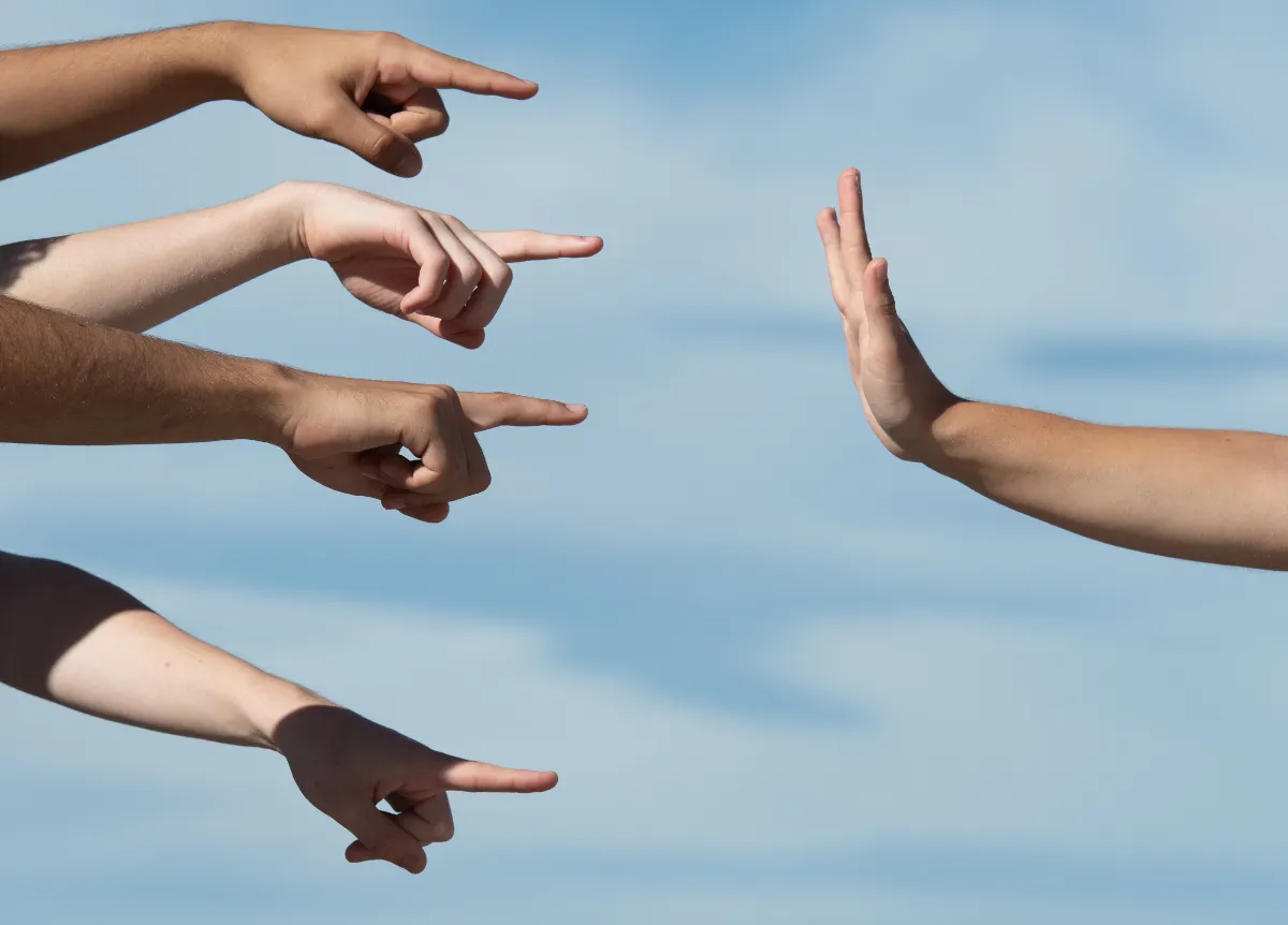 Fingers pointing at a hand defending itself