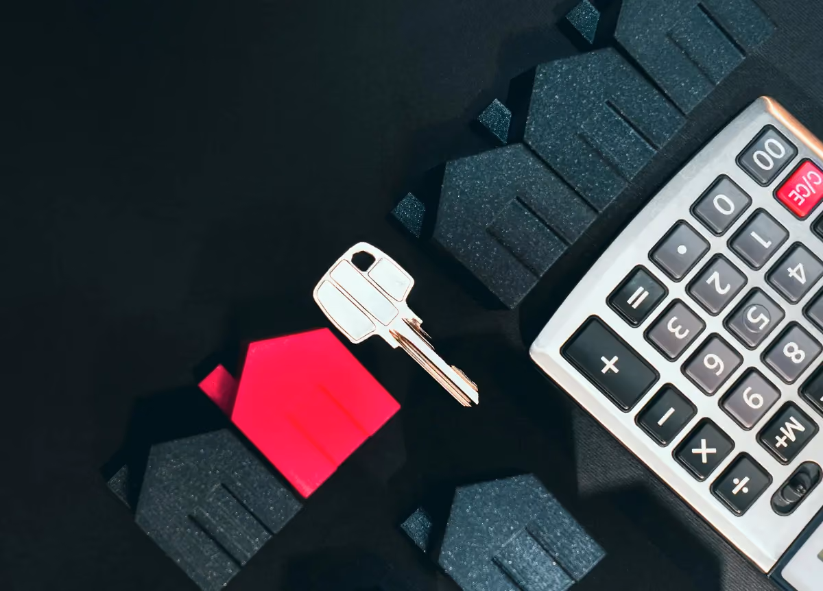 Little red model of house lying next to calculator