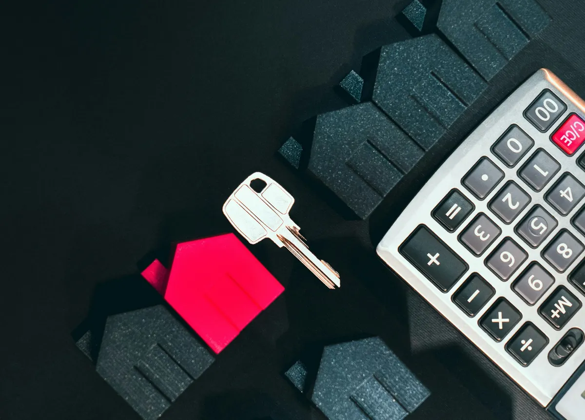 Little red model of house lying next to calculator