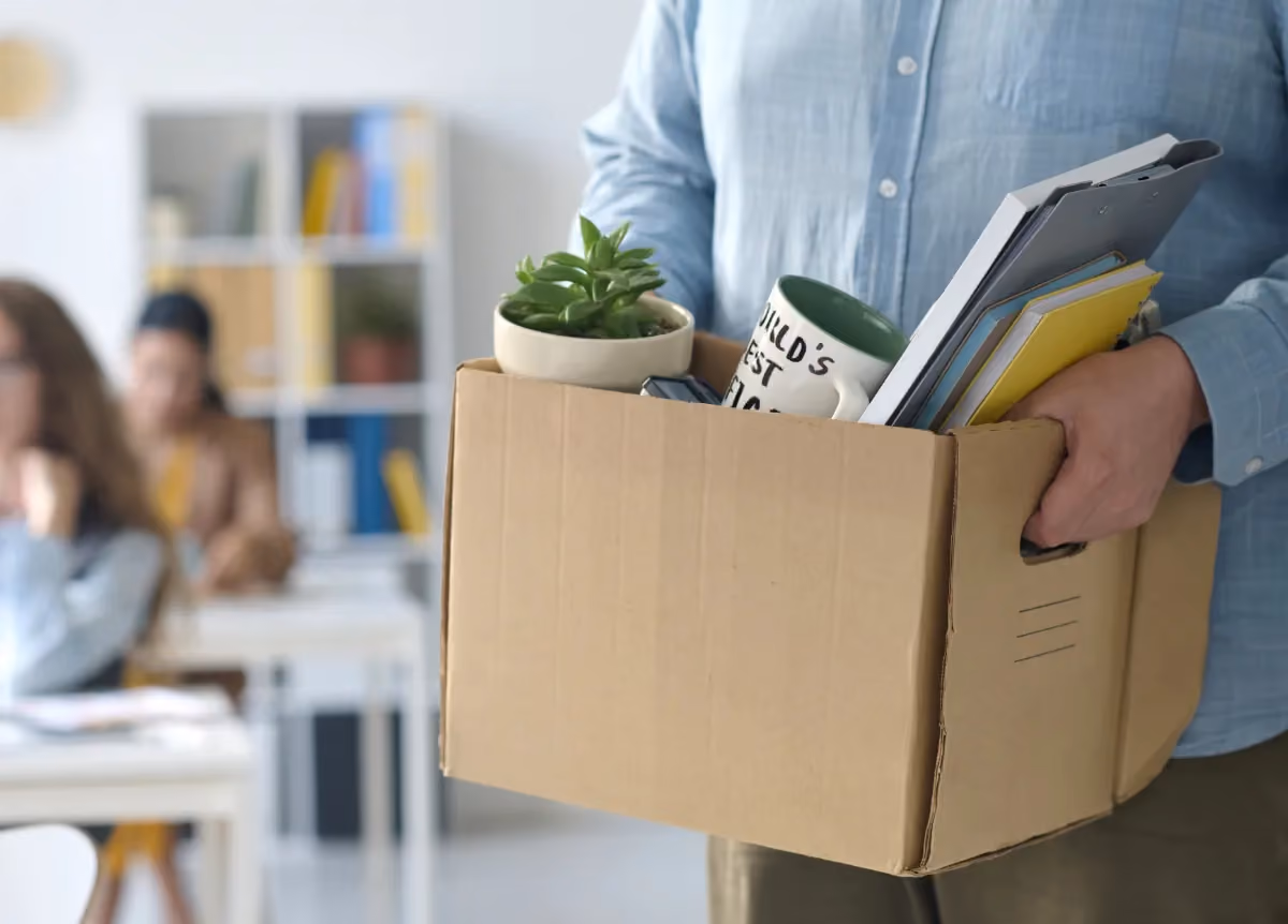 Person leaving office holding a box of personal belongings