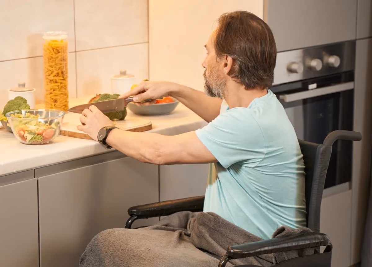 Man in wheelchair prepping food at lowered kitchen counter