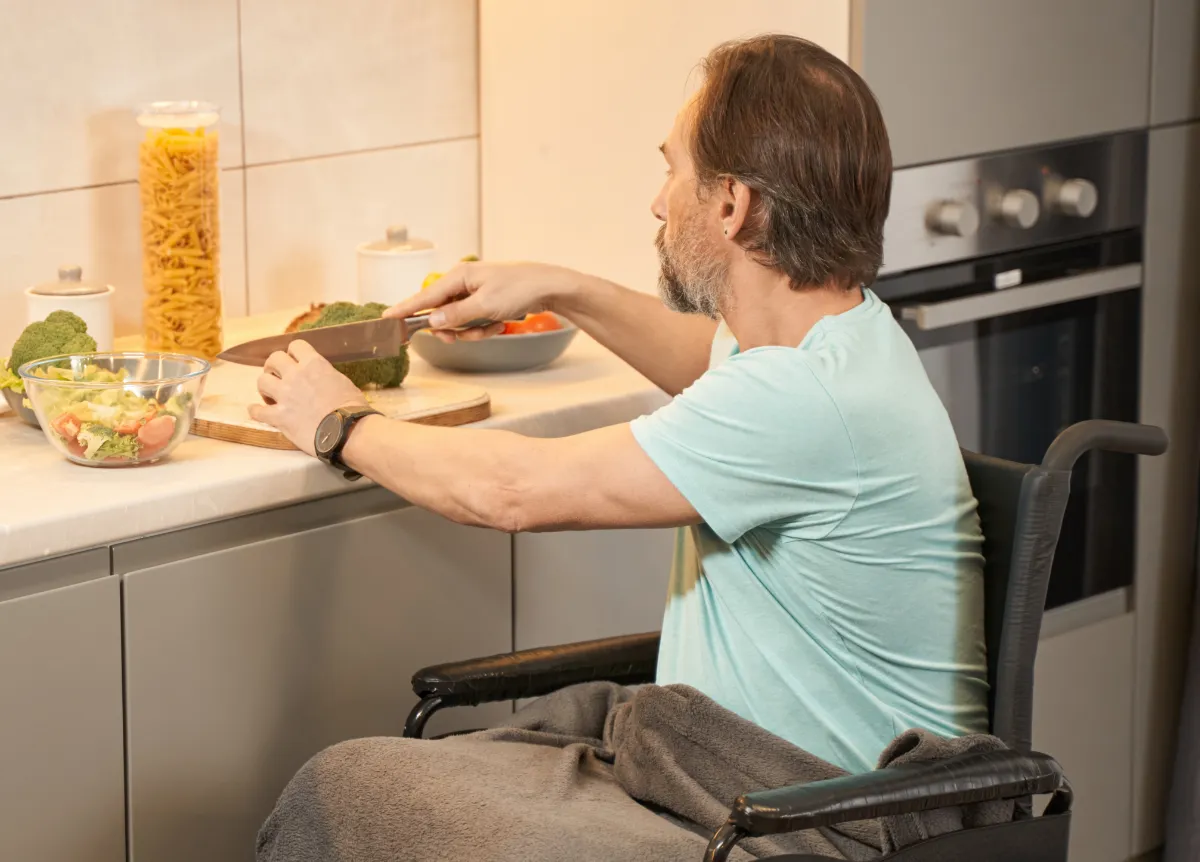 Man in wheelchair prepping food at lowered kitchen counter