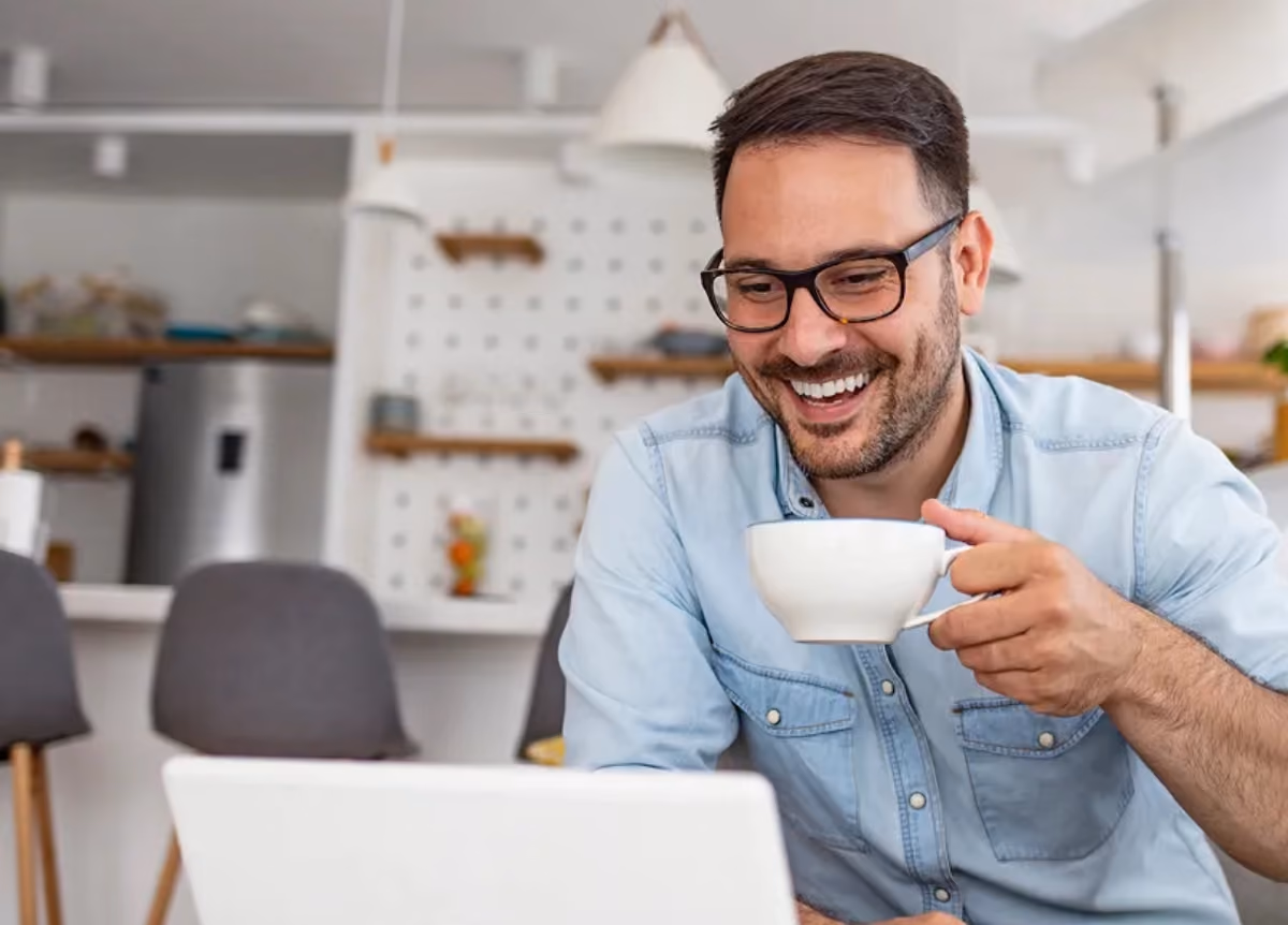 Happy landlord drinking coffee and looking at laptop