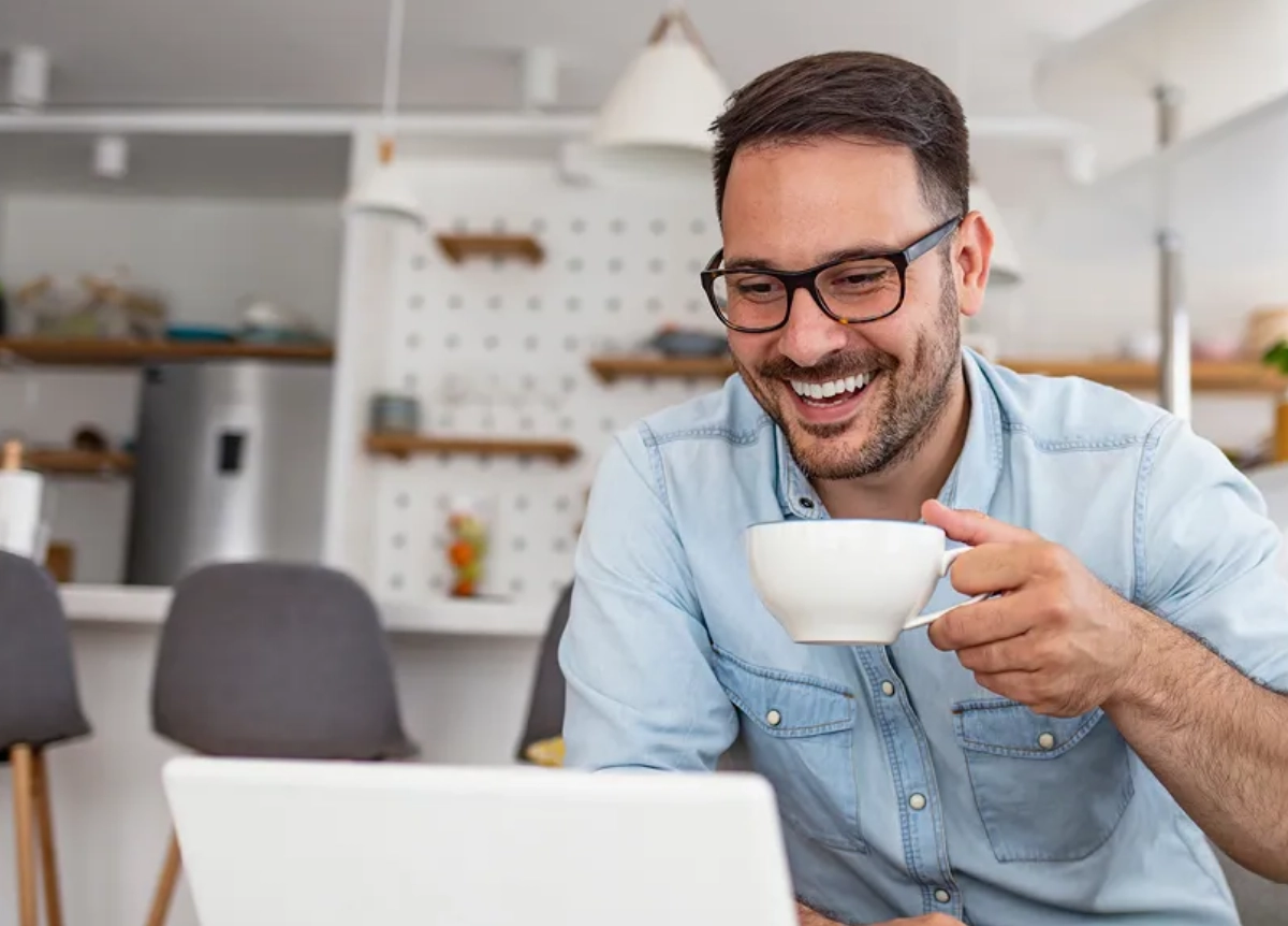 Happy landlord drinking coffee and looking at laptop
