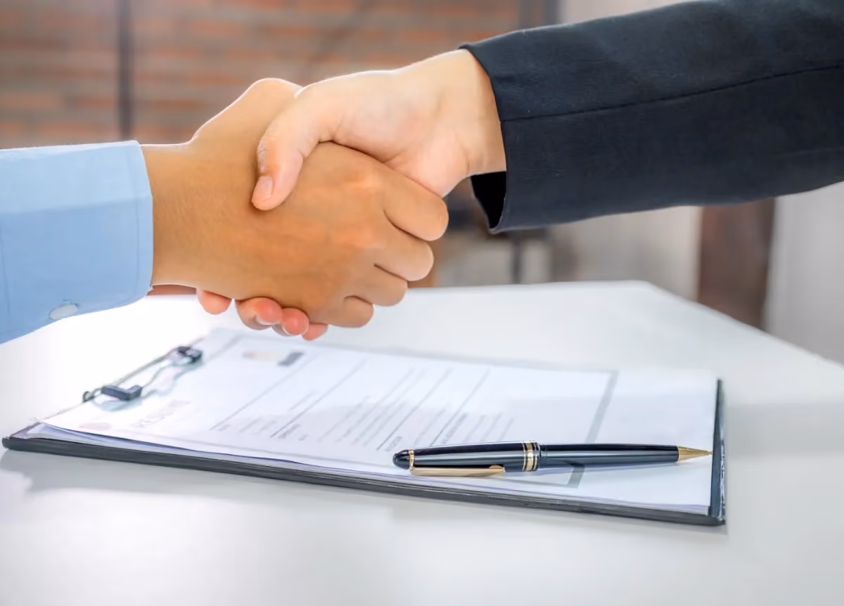 Businesspeople shaking hands above a contract