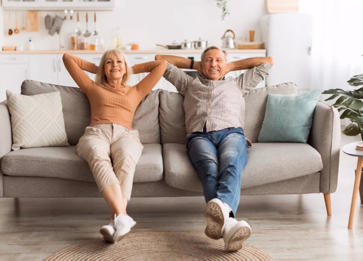 Two older people smiling on couch