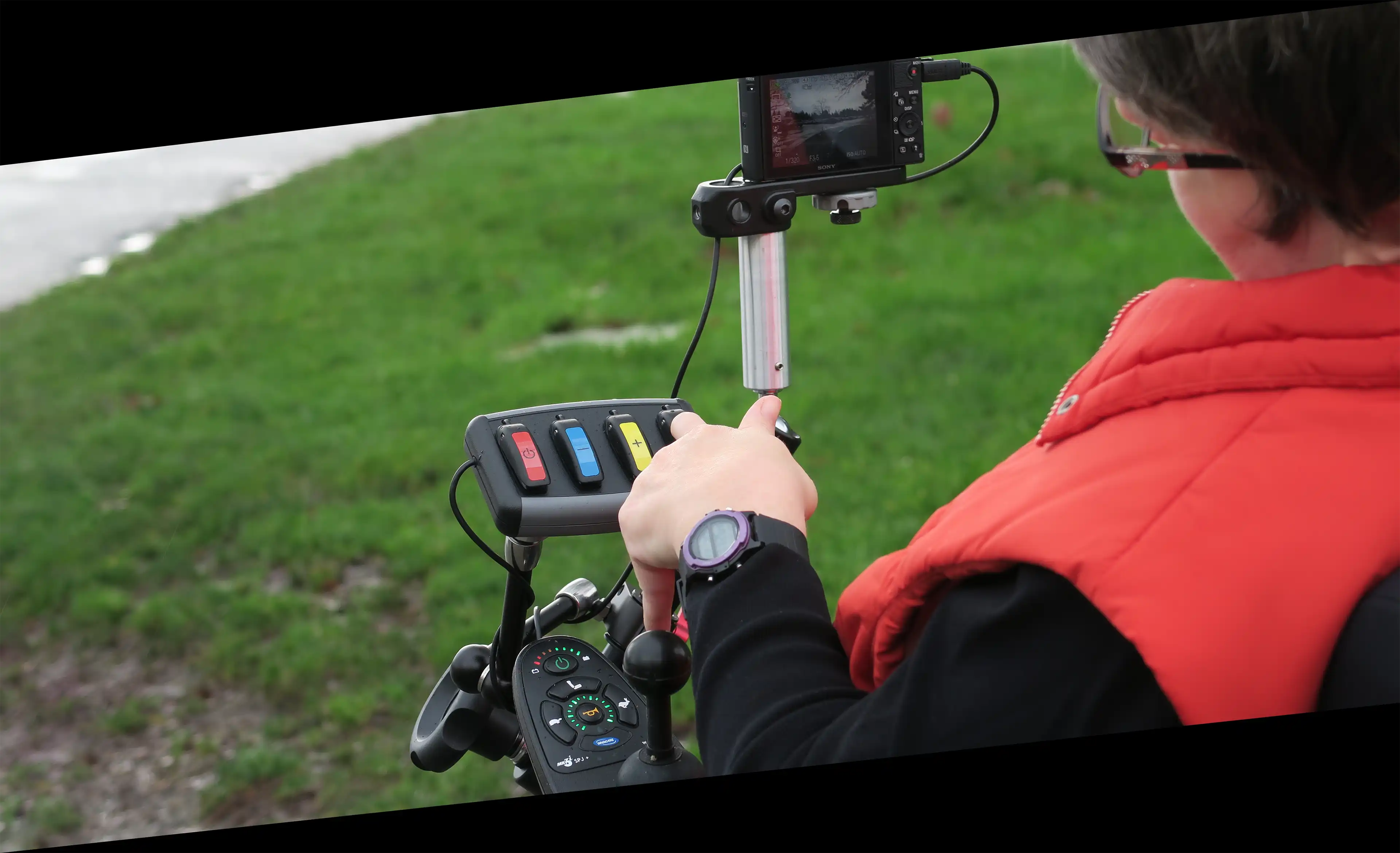 A CanAssist client using wheelchair-mounted assistive tech with buttons and a camera