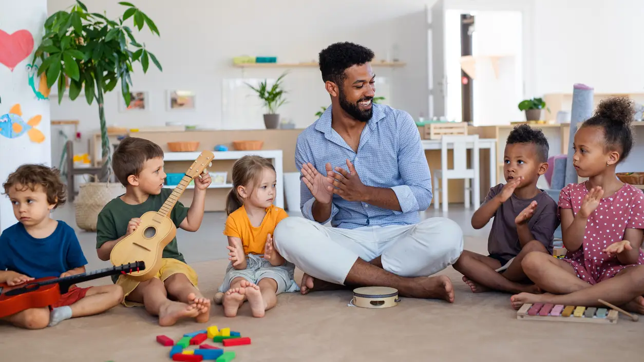 5 children and an early childhood educator sitting and playing music