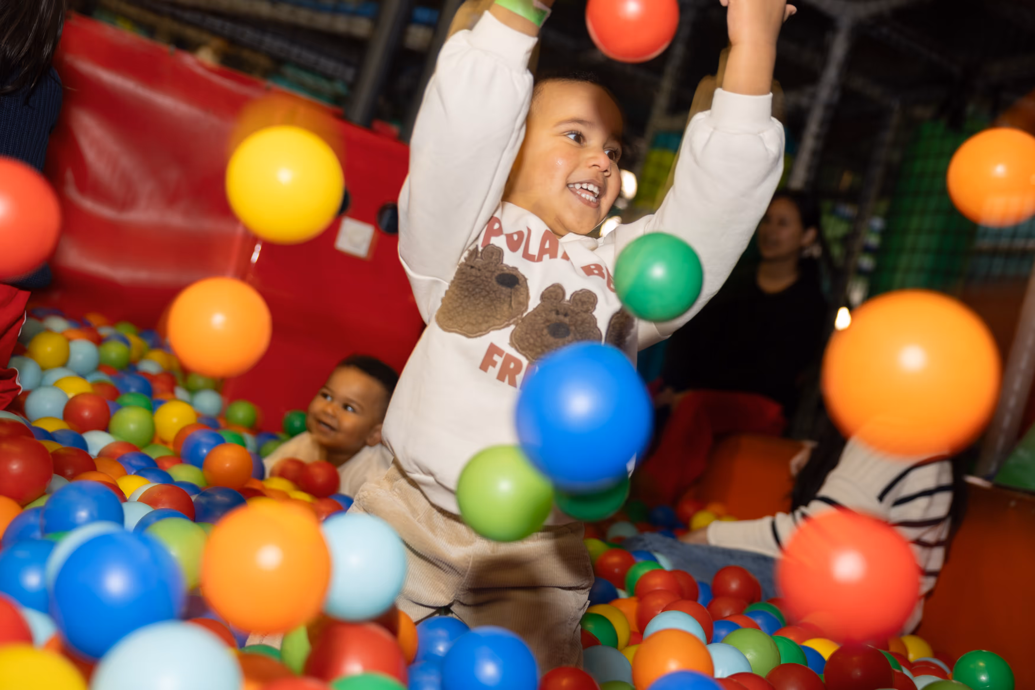 A child throwing balls in a ball pool having fun