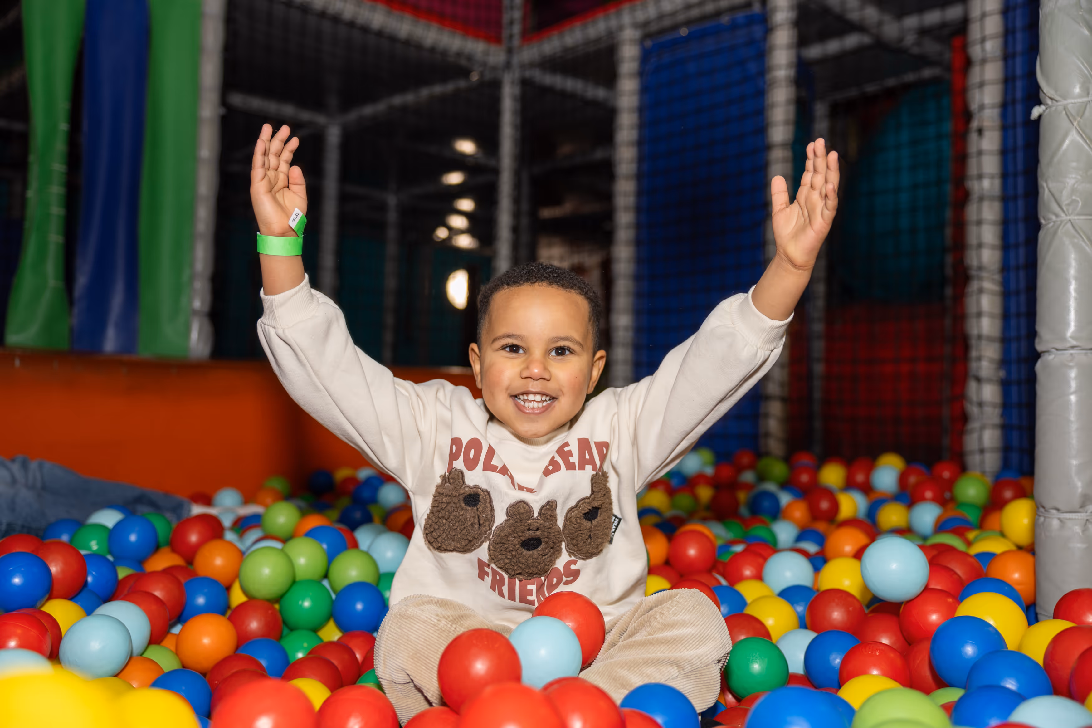 Child playing in the ball pool with arms up. 