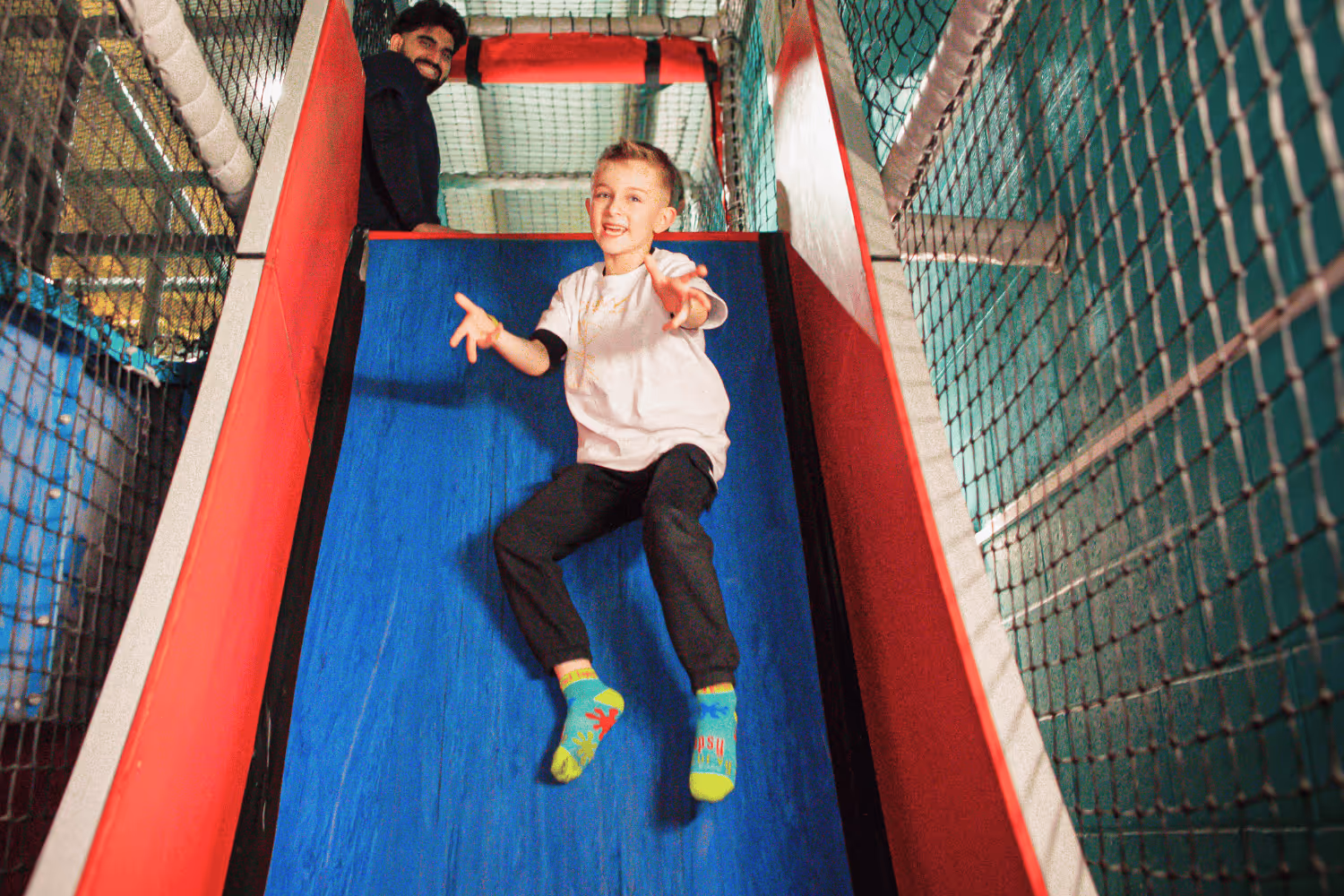 Child sliding down the drop slide striking a cool pose 