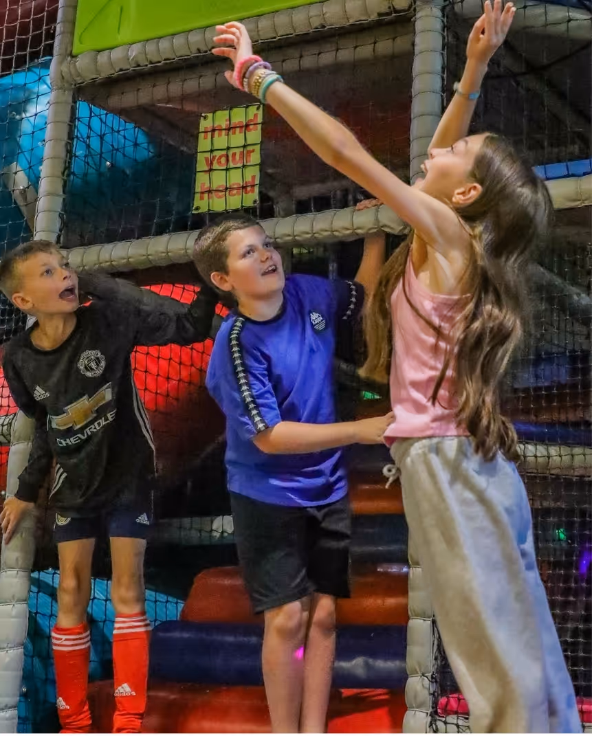 Children playing enthusiastically in indoor soccer training facility