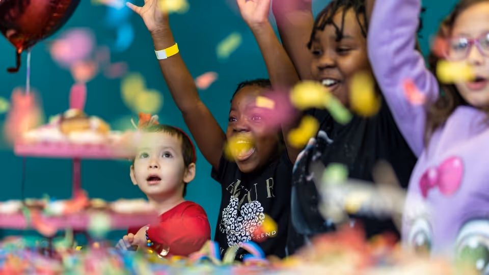 Kids celebrating a birthday with confetti falling in front of them. 