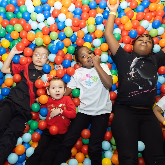 Children playing and posing in a colorful ball pit