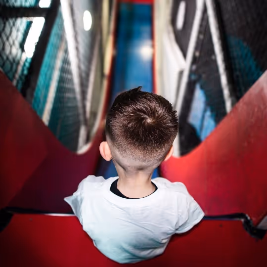 A child sat on the edge of a drop slide ready to take the leap.