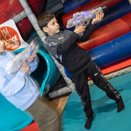 Boy playing with laser tag toys at indoor playground or activity center
