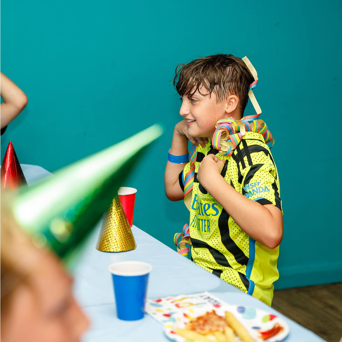 Boy in bright jersey celebrates with party streamers and birthday party supplies