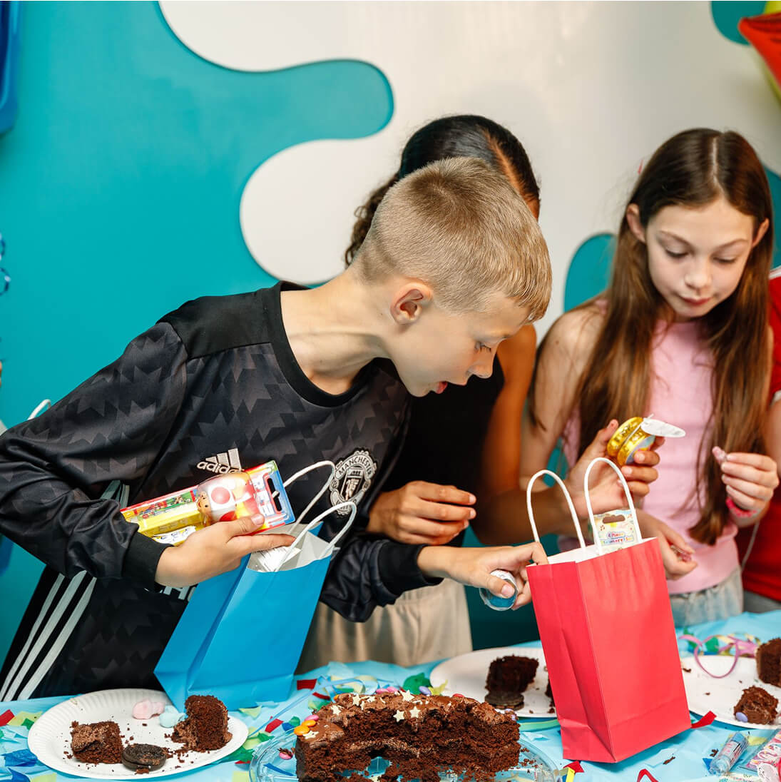 Children enjoying chocolate cake and party gift bags at birthday celebration
