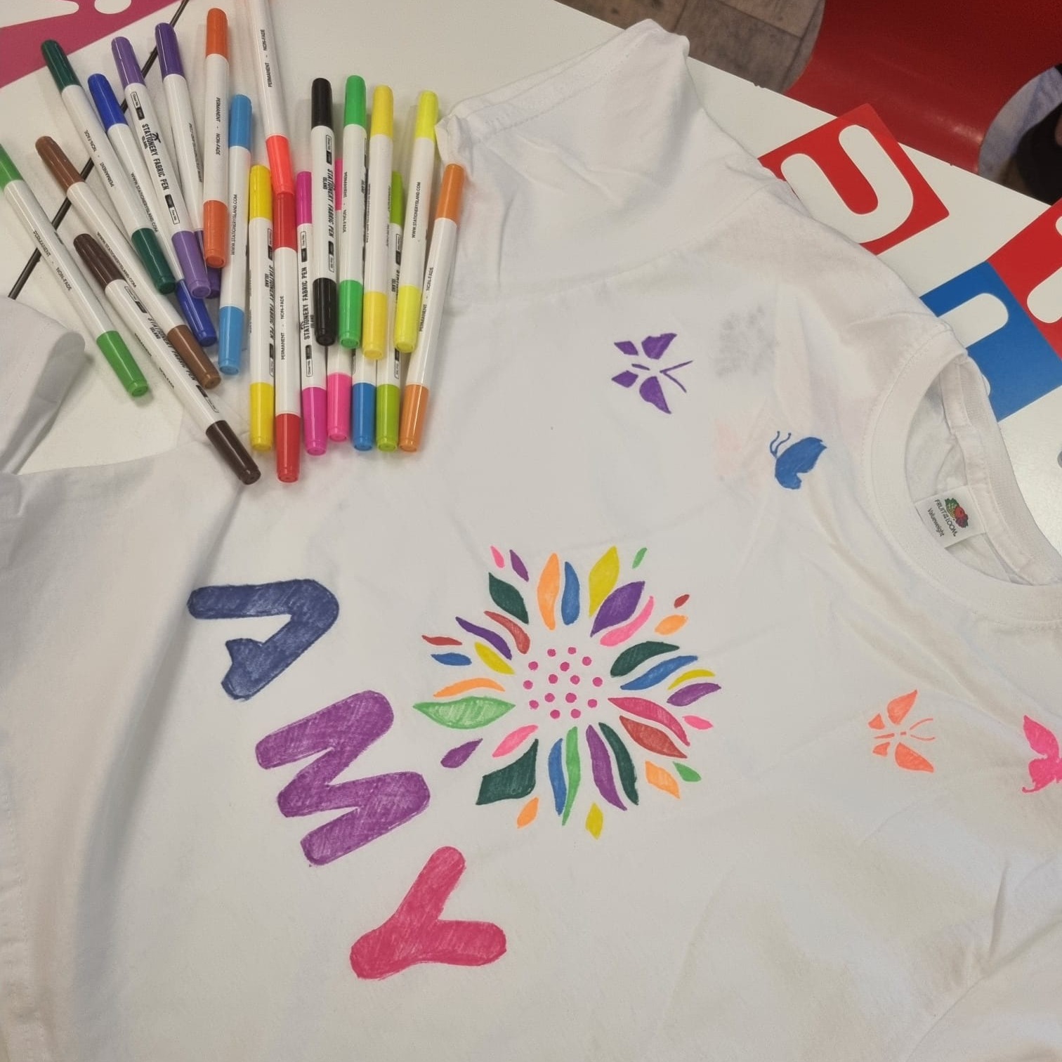 Colourful flower and marker design on white shirt with scattered markers