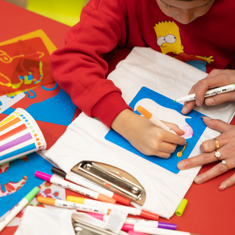 Child drawing on blue board with colorful markers and clipboard