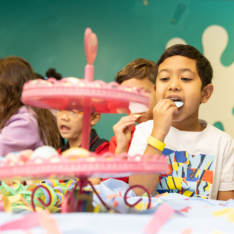 Children enjoying treats from a colorful pink birthday party dessert stand