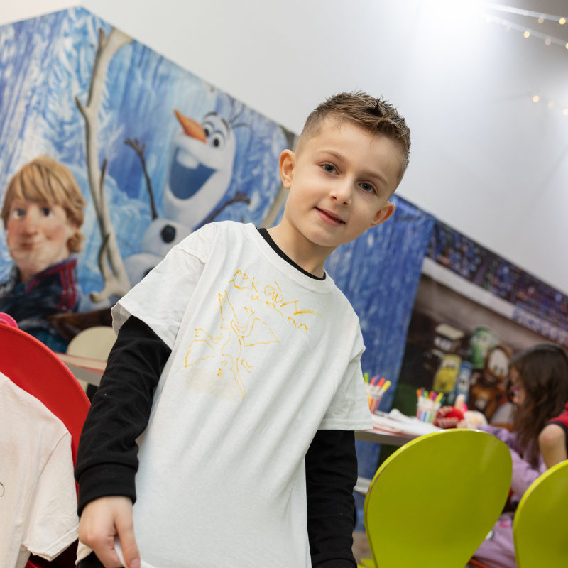 Boy standing in front of Frozen movie poster with Olaf and Kristoff