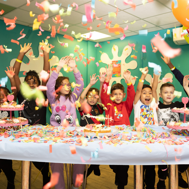 Excited children throwing colorful confetti at a birthday party celebration