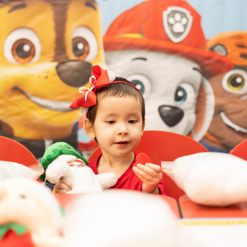 Child with red bow surrounded by Paw Patrol cartoon dog characters