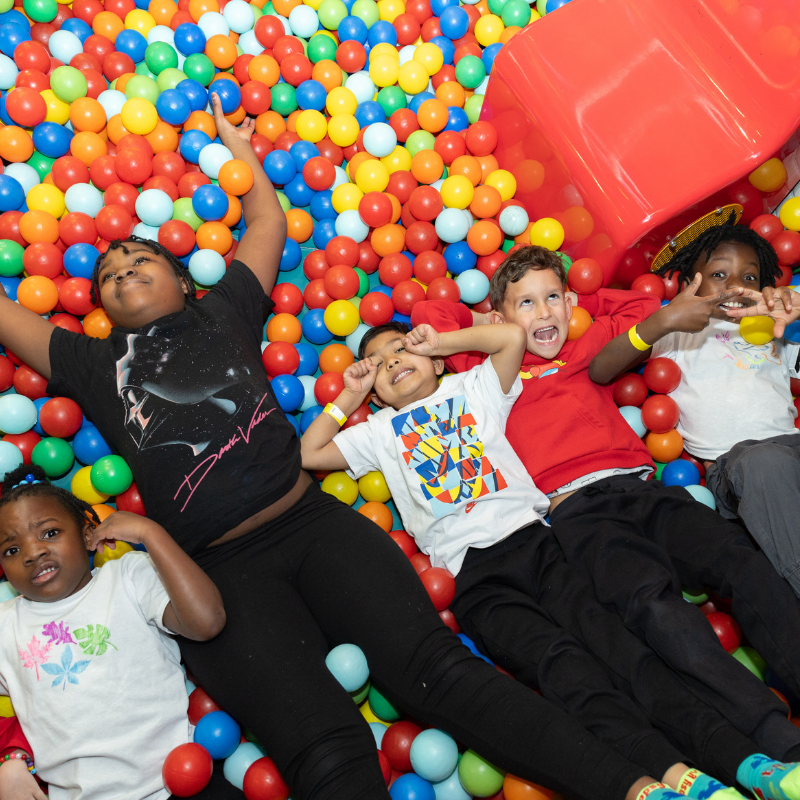 Children playing and laughing in a colorful ball pit