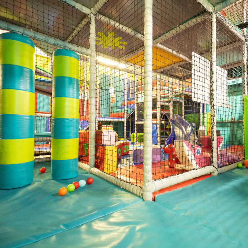 Colorful indoor children's play area with nets, slides, and soft play balls